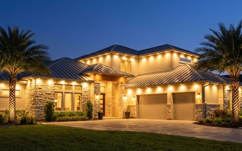 Modern stone and stucco home at dusk, individual warm white bulbs set into track under every eave.
